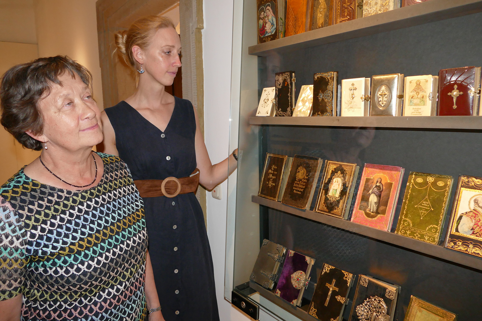 Maria Kunzelmann und Museumschefin Carola Marie Schmidt (rechts) betrachten die ausgestellten Gesang- und Gebetsbücher als Zeugnisse der Volksfrömmigkeit.